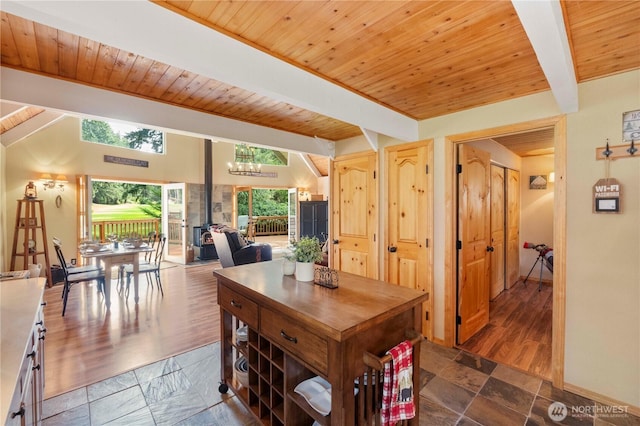 dining room featuring beam ceiling, wood ceiling, and stone tile flooring