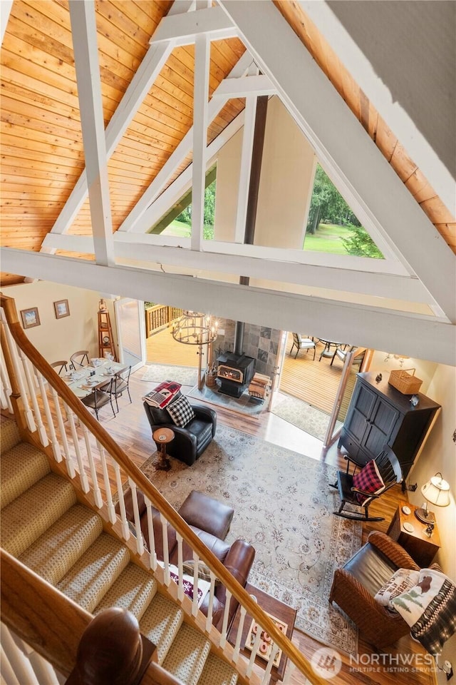 living area with a wealth of natural light, beam ceiling, wood ceiling, and a wood stove