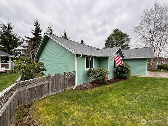 view of home's exterior with fence, a lawn, and roof with shingles