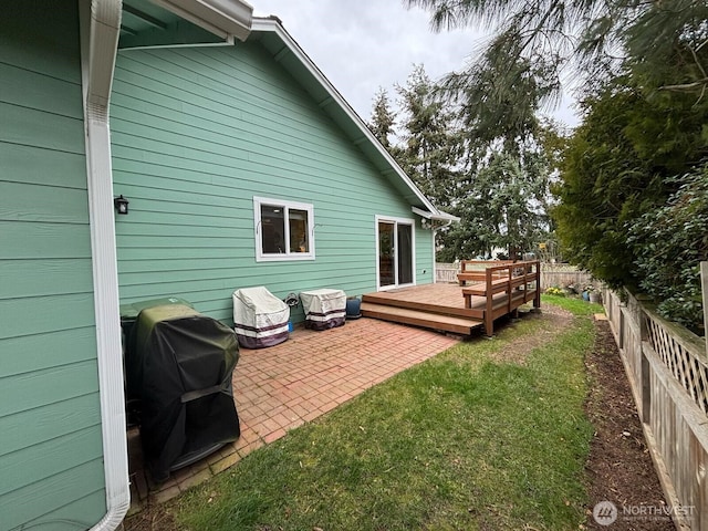 rear view of property featuring a patio area, a lawn, a wooden deck, and a fenced backyard