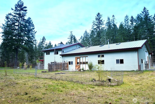 back of house featuring a yard, fence, and metal roof