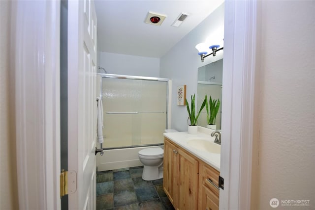 bathroom featuring visible vents, toilet, vanity, and shower / bath combination with glass door