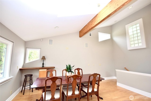 dining space with lofted ceiling with beams, baseboards, and light wood finished floors