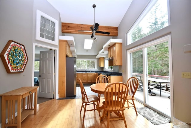 dining area with light wood finished floors, beam ceiling, and a skylight