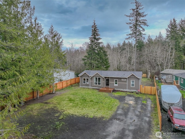 view of front of property with a wooded view, a front yard, and fence