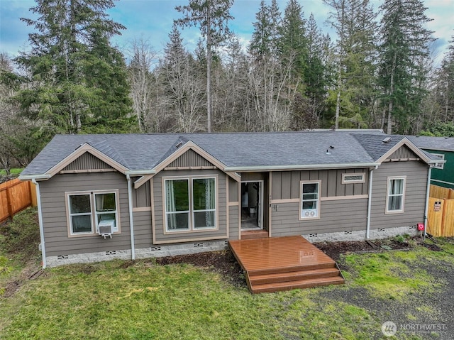 view of front of home featuring a front lawn, fence, board and batten siding, a shingled roof, and crawl space