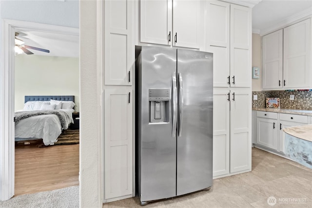 kitchen featuring decorative backsplash, a ceiling fan, stainless steel refrigerator with ice dispenser, and white cabinetry