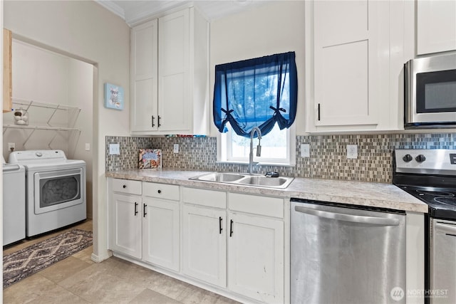 kitchen featuring independent washer and dryer, a sink, appliances with stainless steel finishes, light countertops, and decorative backsplash