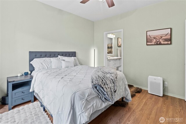 bedroom with ceiling fan, connected bathroom, baseboards, and wood finished floors
