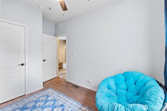 sitting room featuring visible vents, baseboards, ceiling fan, and wood finished floors