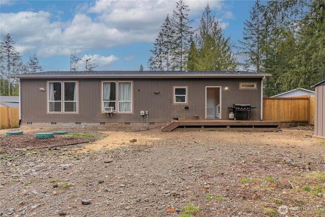 rear view of property featuring a deck, fence, and crawl space