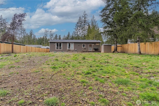 rear view of house with an outbuilding, a fenced backyard, and a shed