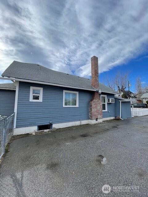 exterior space with a chimney, an AC wall unit, and fence