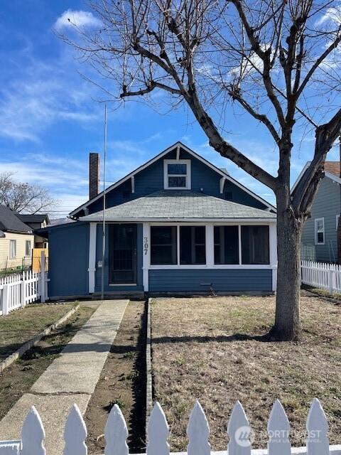 bungalow-style house with a shingled roof, a sunroom, and fence