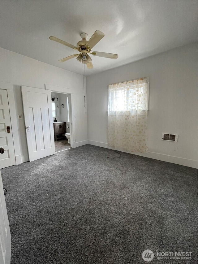 unfurnished bedroom featuring visible vents, ensuite bathroom, baseboards, and dark carpet