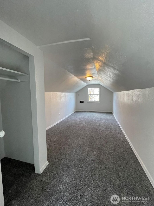 additional living space featuring visible vents, baseboards, vaulted ceiling, a textured ceiling, and carpet flooring