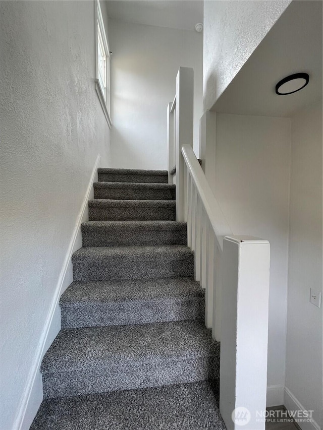 stairway with baseboards and a textured wall