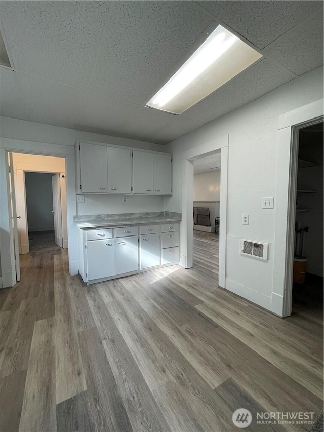 kitchen with white cabinetry, light countertops, visible vents, and light wood-type flooring