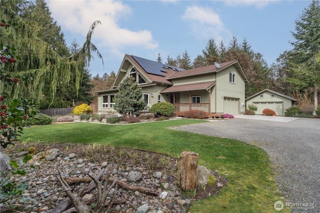 view of front of property with roof mounted solar panels, a porch, gravel driveway, a front yard, and a garage