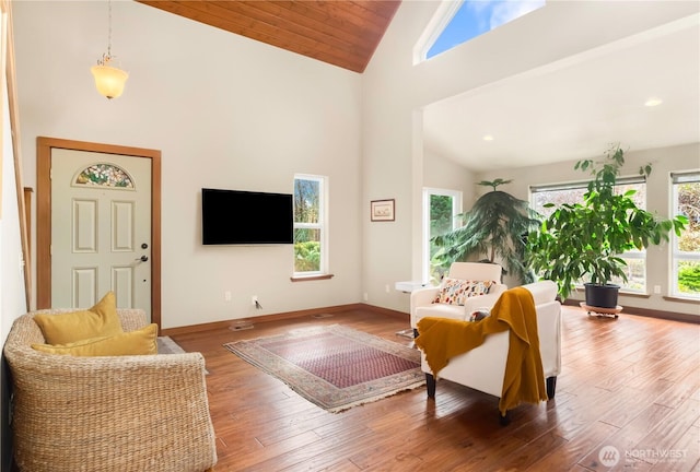 living room featuring a wealth of natural light, high vaulted ceiling, baseboards, and wood finished floors