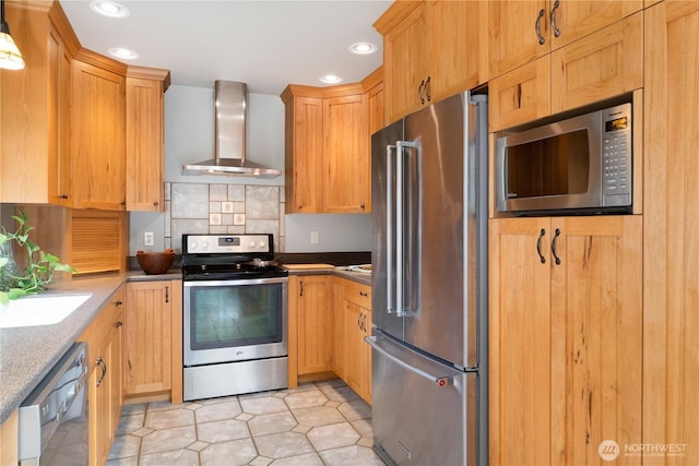 kitchen featuring wall chimney range hood, light tile patterned floors, recessed lighting, appliances with stainless steel finishes, and a sink