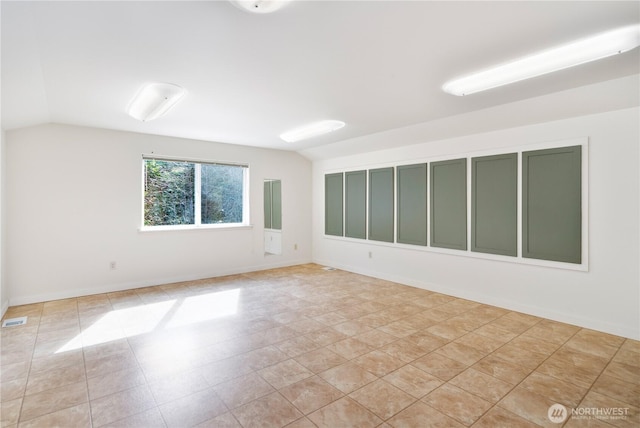 empty room with lofted ceiling, baseboards, and visible vents