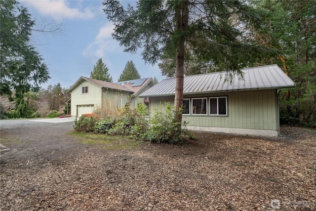 view of front of home with solar panels, driveway, and metal roof