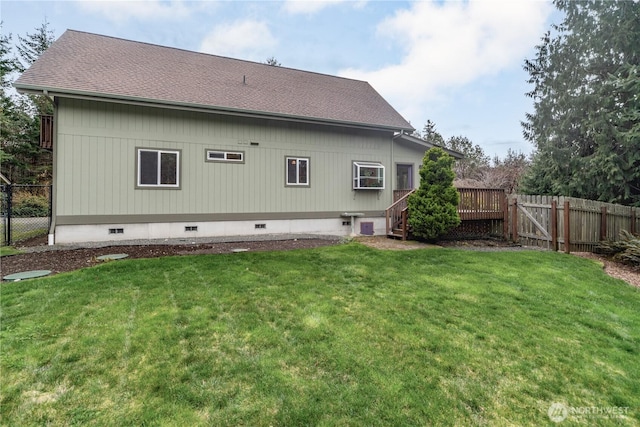 back of property with crawl space, a lawn, roof with shingles, and fence