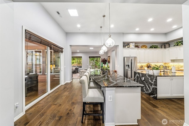 kitchen with a center island, dark wood-style flooring, white cabinets, and stainless steel fridge with ice dispenser
