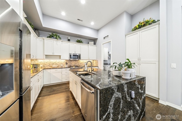 kitchen featuring decorative backsplash, stainless steel appliances, dark wood-style flooring, a sink, and visible vents