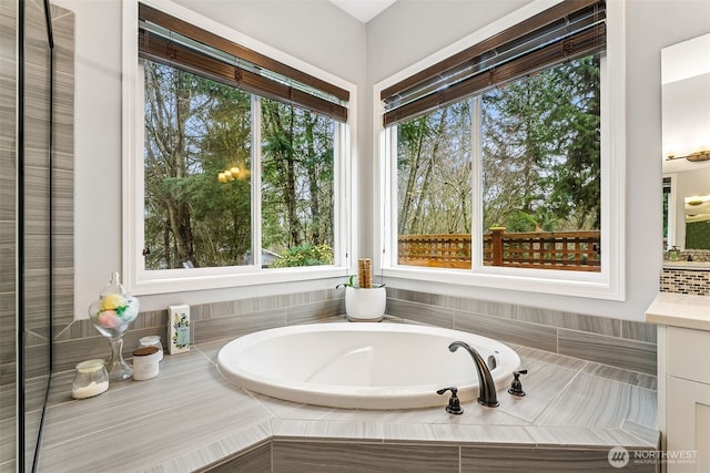 full bath featuring a healthy amount of sunlight, vanity, and a garden tub