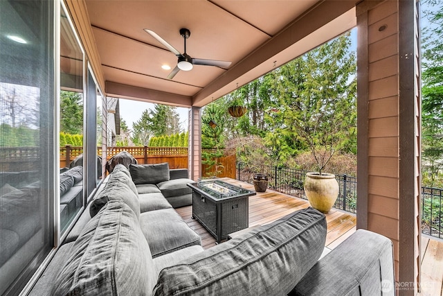 view of patio / terrace with a deck, fence, a ceiling fan, and an outdoor living space with a fire pit