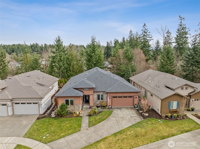 view of front of property with concrete driveway, board and batten siding, stone siding, a front yard, and an attached garage