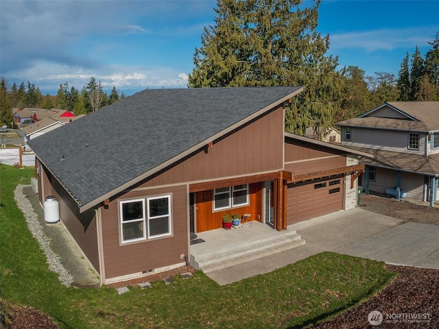 view of front of home featuring driveway, a front lawn, roof with shingles, and an attached garage