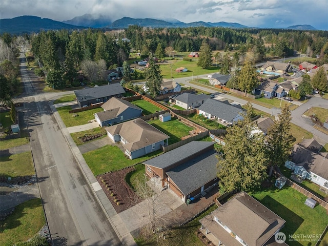 birds eye view of property with a wooded view, a mountain view, and a residential view