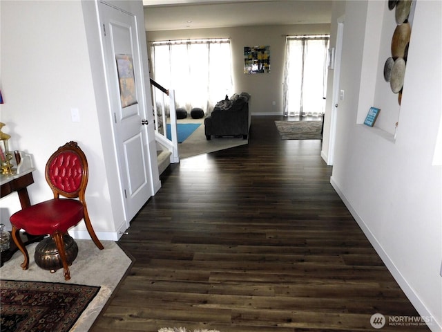 hallway featuring dark wood finished floors, stairway, and baseboards