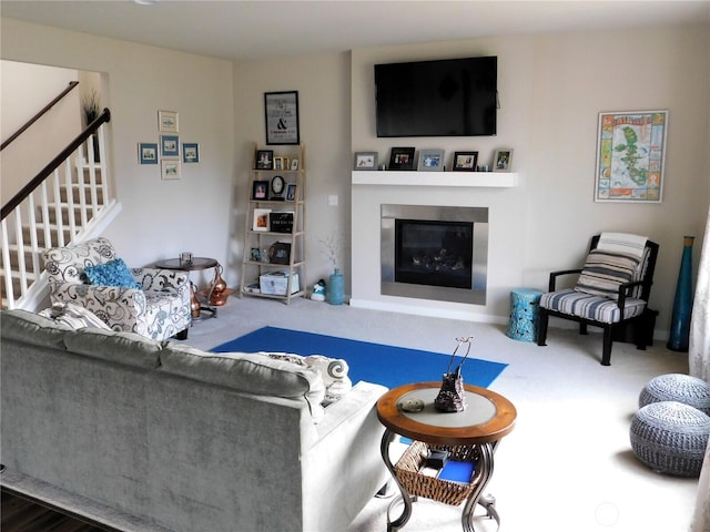 carpeted living area featuring stairs and a glass covered fireplace