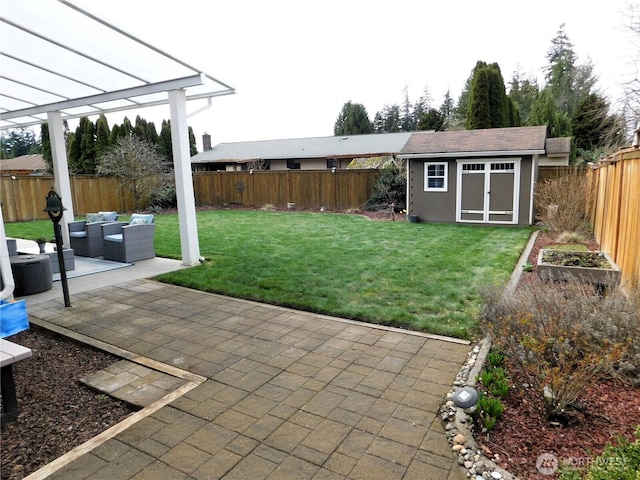 view of yard featuring an outbuilding, an outdoor living space, a patio, a fenced backyard, and a vegetable garden