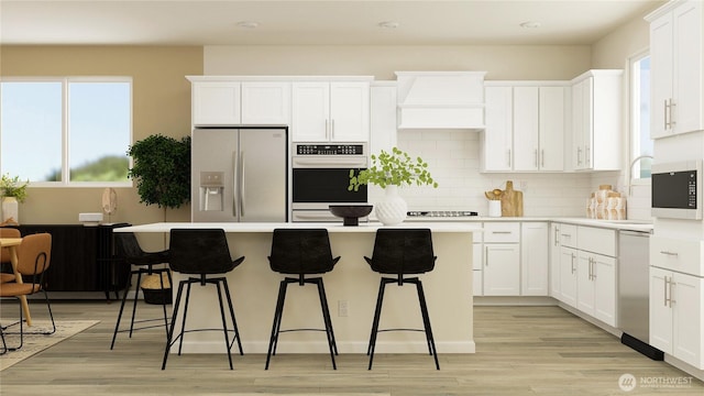 kitchen with custom range hood, stainless steel refrigerator with ice dispenser, a wealth of natural light, and a center island