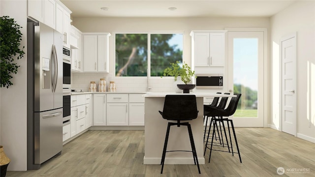 kitchen featuring a kitchen breakfast bar, light wood-style floors, appliances with stainless steel finishes, and white cabinets