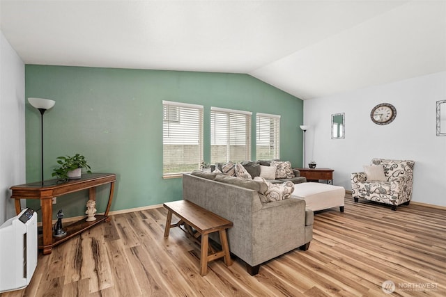 living area featuring baseboards, light wood-type flooring, and lofted ceiling