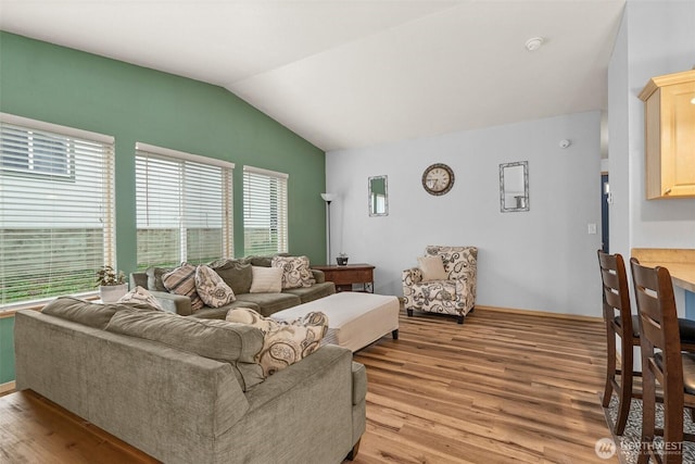 living room featuring light wood finished floors, baseboards, and vaulted ceiling