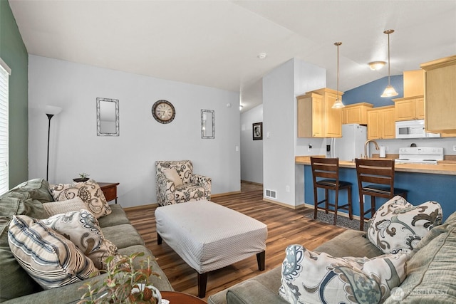 living room featuring visible vents, baseboards, lofted ceiling, and wood finished floors