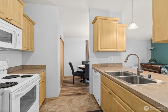 kitchen featuring light brown cabinets, light countertops, hanging light fixtures, white appliances, and a sink
