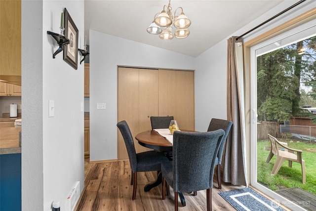 dining room with vaulted ceiling, a notable chandelier, and wood finished floors