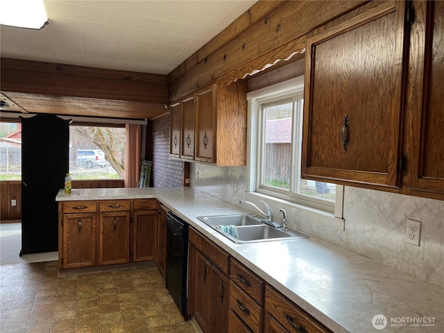 kitchen featuring decorative backsplash, light countertops, a sink, and black dishwasher