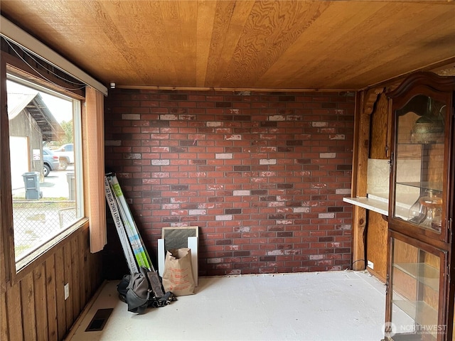 interior space with wood ceiling, brick wall, concrete floors, and visible vents