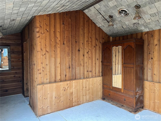 additional living space with wood walls, lofted ceiling, and visible vents