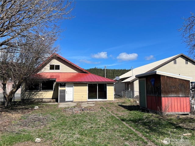 back of property featuring a yard and metal roof