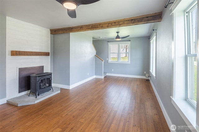 308 S 1st St, Roslyn, WA 98941 - unfurnished living room with a wood stove, beam ceiling, hardwood / wood-style flooring, and ceiling fan